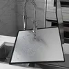 A stainless steel splash guard is being rinsed under a kitchen faucet. Produktbild-Vorschau