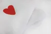 A close-up of white fabric with a red heart design. Produktbild-Vorschau