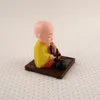 A small figurine of a meditating monk sitting on a wooden base. Produktbild-Vorschau