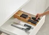 A hand is reaching into a kitchen drawer to take out a knife from a knife block organizer. Other kitchen utensils are also visible in the drawer. Náhled obrázku produktu
