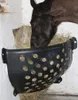A horse eating hay from a black plastic feeder mounted on a wall. Produktbild-Vorschau