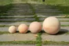 Four terracotta spheres of varying sizes are placed on a pathway with grass growing between the stones. Náhľad obrázku produktu