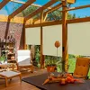 A sunroom or covered patio with wooden beams, glass roof, and brick walls, furnished with outdoor seating and a table. Roller blinds are installed on the windows. Voir les images du produit