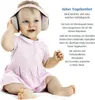 A baby wearing pink headphones and a pink dress, sitting on a white surface. Produktbild-Vorschau