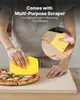 A person is using a yellow scraper to cut a pizza on a pizza stone. Náhľad obrázku produktu