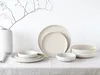 A set of off-white ceramic plates and bowls are arranged on a white tablecloth, with a white vase and a bare branch in the background. Produktbild-Vorschau