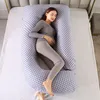 A pregnant woman is sleeping on a bed, using a large U-shaped pregnancy pillow. Náhled obrázku produktu