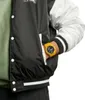 A person's hand wearing a yellow watch is placed in the pocket of a black and white jacket. Náhled obrázku produktu