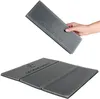 A hand holding a folded gray seat cushion with the brand name "LEGENDWERK" embossed on it, with another folded seat cushion laid out flat in the foreground. Produktbild-Vorschau