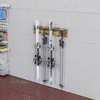 A ski rack mounted on a concrete wall, holding two pairs of skis and poles. Anteprima dell’immagine prodotto