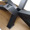 A close-up view of a black metal table base with a wooden floor. Produktbild-Vorschau