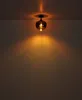 A single ceiling light fixture with a dark brown glass shade is mounted on a white ceiling, casting a warm orange glow on the wall below. Náhled obrázku produktu