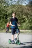 Two children are riding scooters in an outdoor park. Náhľad obrázku produktu