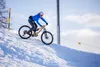 A person riding a mountain bike on a snowy slope. Produktbild-Vorschau
