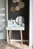 A white vanity table with a round mirror and wooden legs, decorated with wall art and cosmetics, in a room with a dark gray wall. Anteprima dell’immagine prodotto