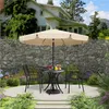 An outdoor patio set with a table, chairs, and an umbrella, set in a garden with a stone wall and a house in the background. Produktbild-Vorschau