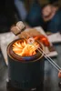Two marshmallows are being toasted over a small portable fire pit. Produktbild-Vorschau