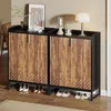A shoe cabinet with two doors, decorated with a wood-grain pattern and a geometric design at the bottom. Several pairs of shoes are placed on the floor in front of and underneath the cabinet. A framed picture, a lamp, and decorative candle holders are on t Produktbild-Vorschau