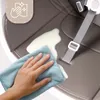 A hand is wiping a spill off a high chair seat with a blue cloth. There is a graphic in the upper left corner indicating easy cleaning. Voir les images du produit