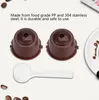 Two brown coffee capsules and a white measuring spoon are laid out on a white background, with some coffee beans scattered around. Produktbild-Vorschau