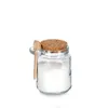 A small glass jar filled with white granular material, sealed with a cork lid and a small wooden spoon attached to the side. Anteprima dell’immagine prodotto