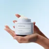 Hands holding a jar of Kerasilk hair mask against a light blue sky background. Anteprima dell’immagine prodotto
