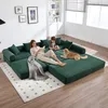 A family is relaxing on a modular green sofa in a living room. Produktbild-Vorschau