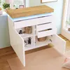 A white sideboard with a wooden top, featuring open drawers and doors, placed in a room with a window and a rug. Podgląd zdjęcia produktu