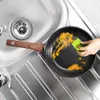 A hand is cleaning a frying pan in a kitchen sink. Produktbild-Vorschau