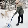 A woman is shoveling snow in a snowy outdoor environment. Produktbild-Vorschau