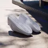 The underside of two white Adidas VL Court 3.0 shoes are shown on a concrete surface with shadows. Produktbild-Vorschau