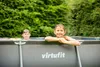 Two children are in a rectangular swimming pool outdoors, surrounded by green trees. Produktbild-Vorschau