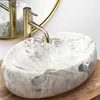A marble vessel sink with a gold faucet and drain. Produktbild-Vorschau