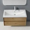 A modern bathroom vanity with a sink and faucet, set against a gray wall and a speckled floor. Produktbild-Vorschau