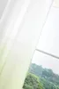 A sheer curtain with a gradient color from white to green is shown in front of a window with a view of trees. Produktbild-Vorschau