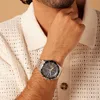 A man wearing a watch on his wrist, with his hand resting on his chin. Produktbild-Vorschau