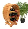 A wooden barrel-shaped wine rack holding six bottles of red wine, with a potted plant in the background. Náhled obrázku produktu