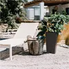 A lounge chair and a potted plant are set up on a gravel patio next to a building. Produktbild-Vorschau