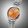 A close-up studio shot of a men's wristwatch with an orange dial and a silver metal bracelet, set against a gradient gray background. Voir les images du produit