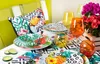 A table setting with tropical-themed dishes, glasses, and flowers. Produktbild-Vorschau