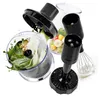 A collage of various attachments and ingredients for a hand blender, including a chopper with basil and nuts, a whisk with cream, and chopped fruit. Produktbild-Vorschau