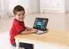 A young boy is sitting at a table and using a toy laptop. Produktbild-Vorschau