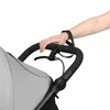 A close-up shot of a person's hand holding the handle of a stroller. Produktbild-Vorschau