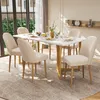 A dining room set with a marble-top table and six beige upholstered chairs with gold metal legs, set on a patterned rug. Náhľad obrázku produktu