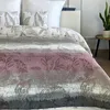 A close-up view of a bed with a patterned comforter and pillows. Náhľad obrázku produktu