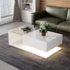 A modern living room scene featuring a white coffee table with a glass top, a green leather sofa, and a bookshelf in the background. Voir les images du produit