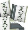Several pillows and a folded duvet cover with a green leaf pattern are arranged on a white background. Produktbild-Vorschau