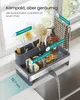 A kitchen sink organizer with various cleaning tools and a soap dispenser, placed on a countertop next to a sink with water running. Produktbild-Vorschau