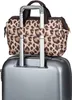 A leopard print bag is attached to the handle of a silver suitcase. Produktbild-Vorschau