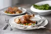 Two plates of roasted chicken with vegetables and a bowl of salad in the background. Anteprima dell’immagine prodotto